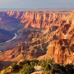 The walking path in to the Grand Canyon is surrounded by beautiful red rocks and a river.